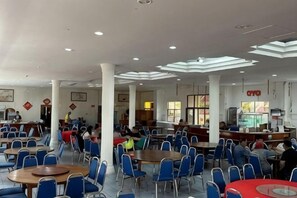 Un amplio comedor interior con varias mesas y sillas, una barra y una zona de cocina a la vista.