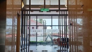 A hotel entrance with a glass door, a sign indicating the name 'KELUAR', and a view of the outside through the glass.