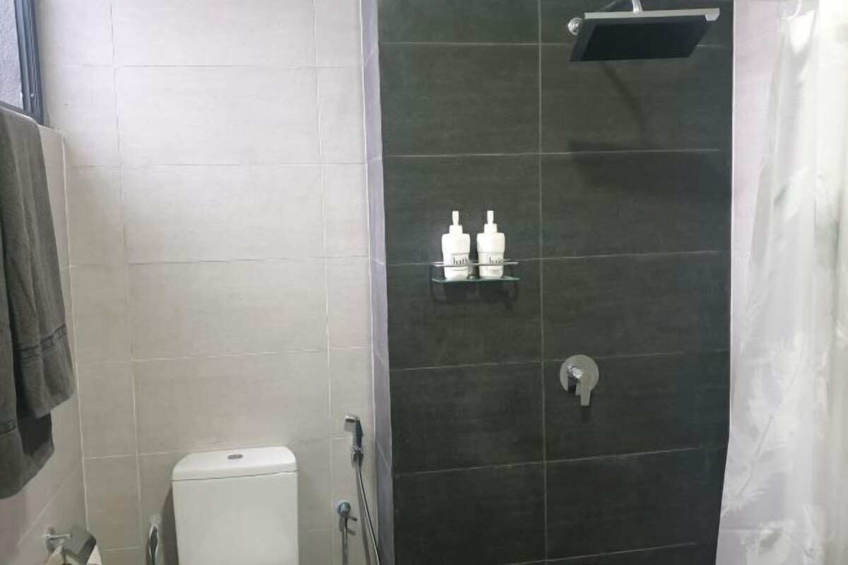 Casa de banho com sanita, chuveiro e um armário com produtos de higiene pessoal.