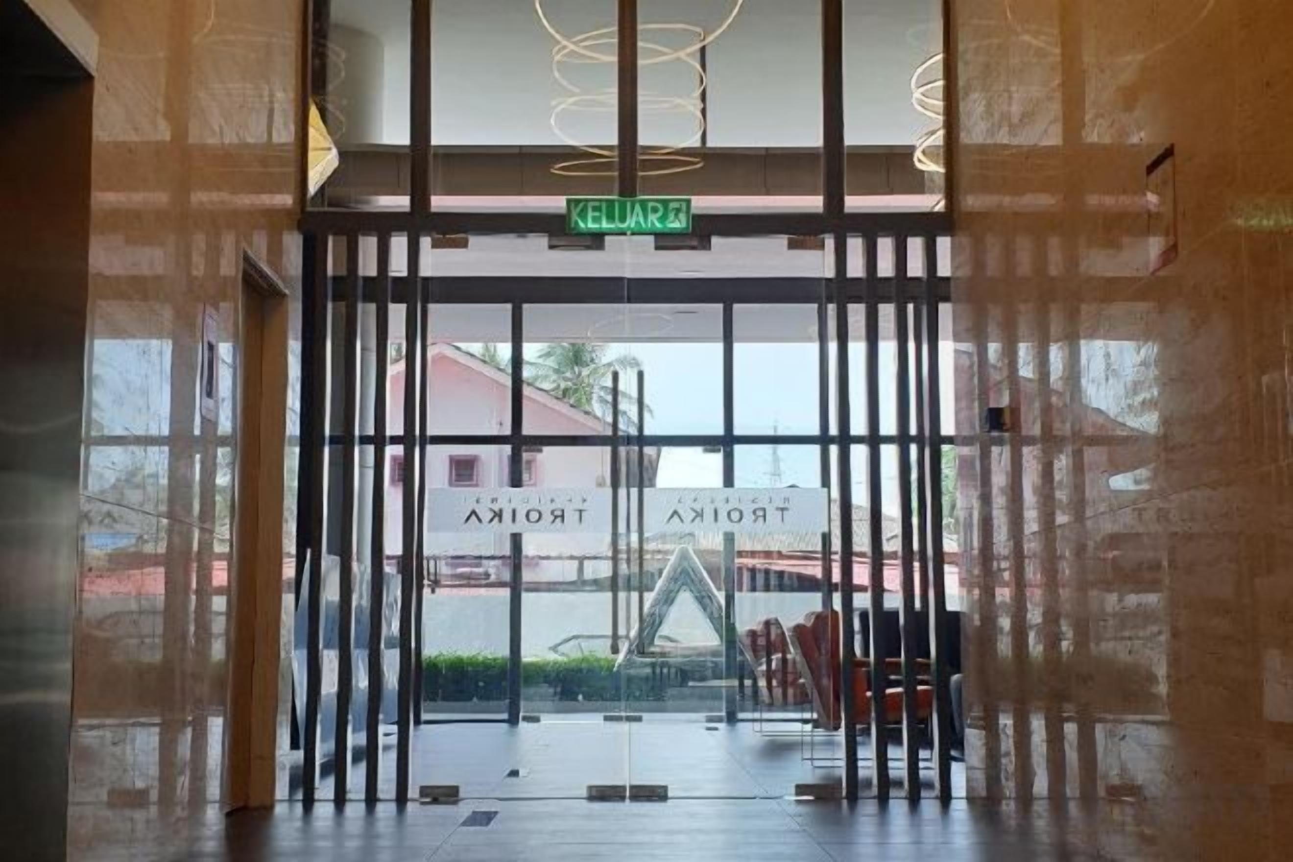 L’entrée d’un hôtel avec une porte en verre, une enseigne indiquant « SORTIE » et une vue sur la rue.