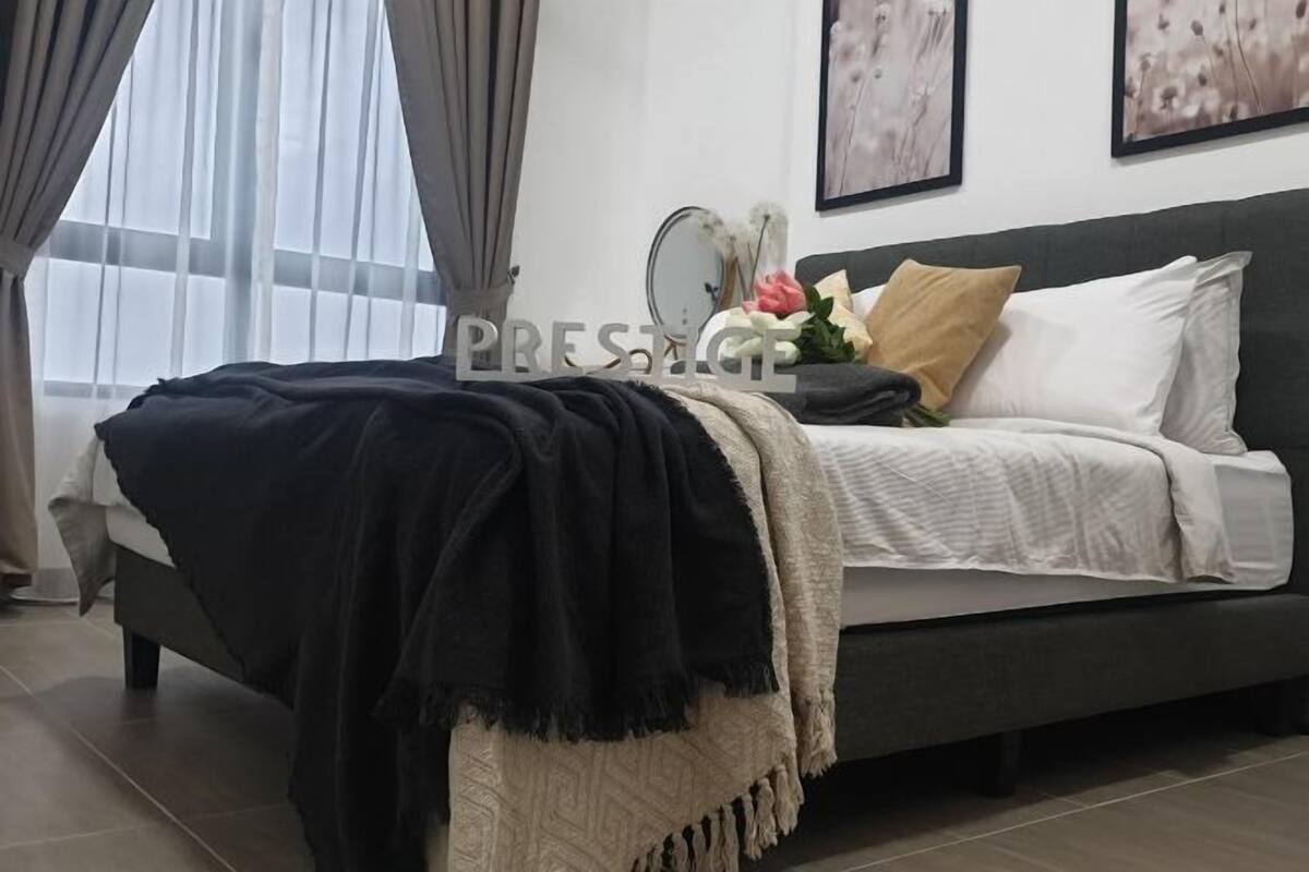 Une chambre à coucher avec un lit, une table de chevet, un miroir et une fenêtre avec des rideaux.