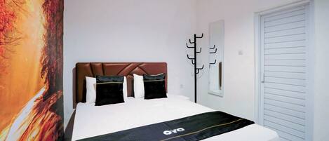 Un dormitorio con cama, cabecera, perchero y puerta.