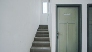 Uma escadaria leva a uma porta com a inscrição "STAFF ONLY", com uma pequena janela acima.