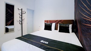 A hotel room with a bed, a coat rack, and a window.