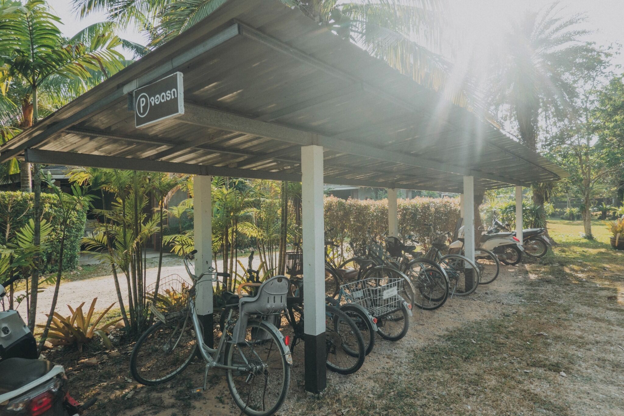 A covered parking area with bicycles and a motorcycle.