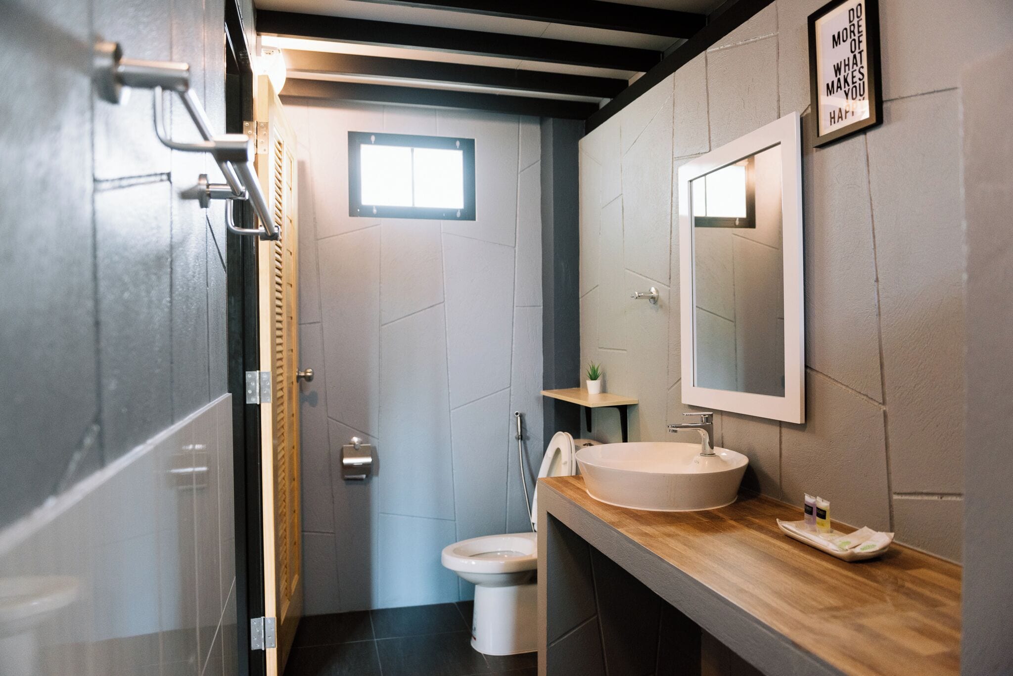 A modern bathroom with a wooden vanity, a large mirror, and a toilet.