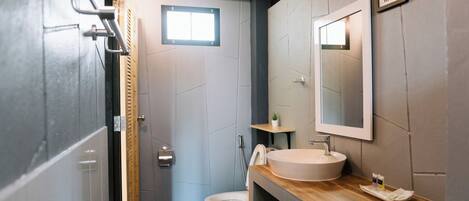 A modern bathroom with a wooden vanity, a large mirror, and a toilet.