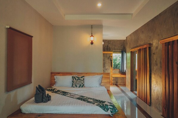 A hotel room with a large bed, wooden headboard, and a hanging light fixture. - Villa Varich (Chumphon)