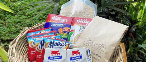 A wicker basket containing various food items including Kellogg's Frosties, Thai-Denmark milk, and a coffee bag.