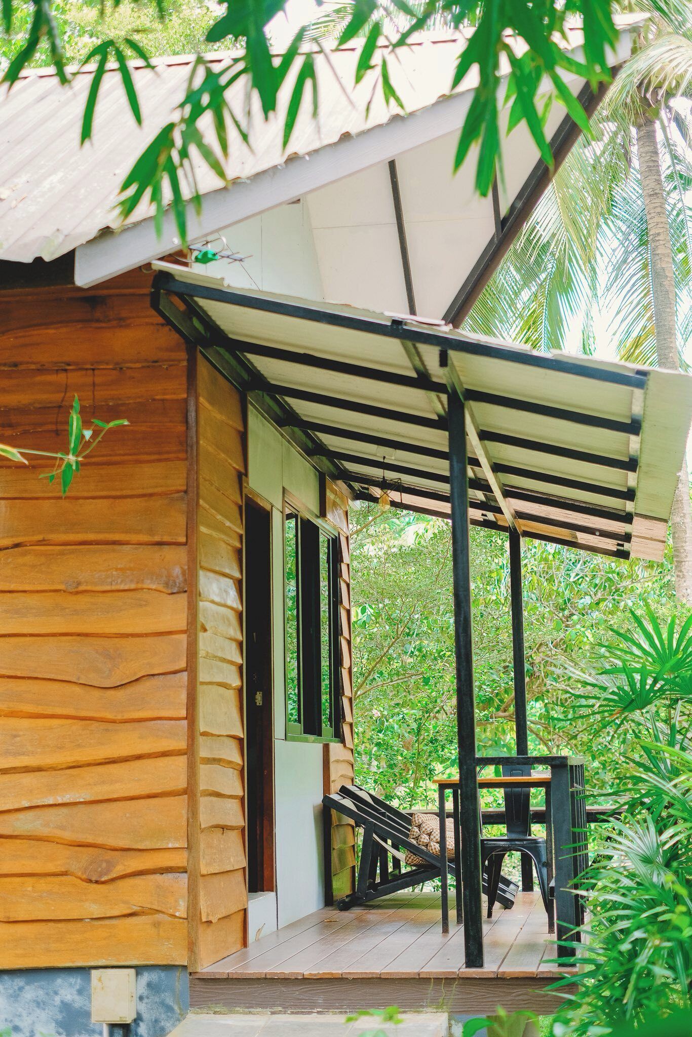 A wooden cabin with a covered porch, a small table, and chairs.