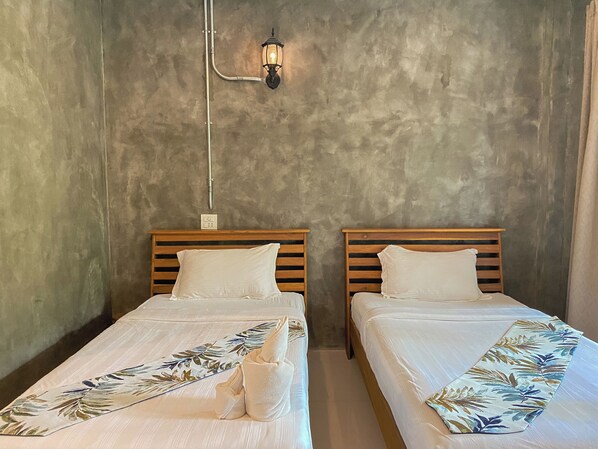 Two single beds with wooden headboards, white linens, and a floral-patterned blanket.