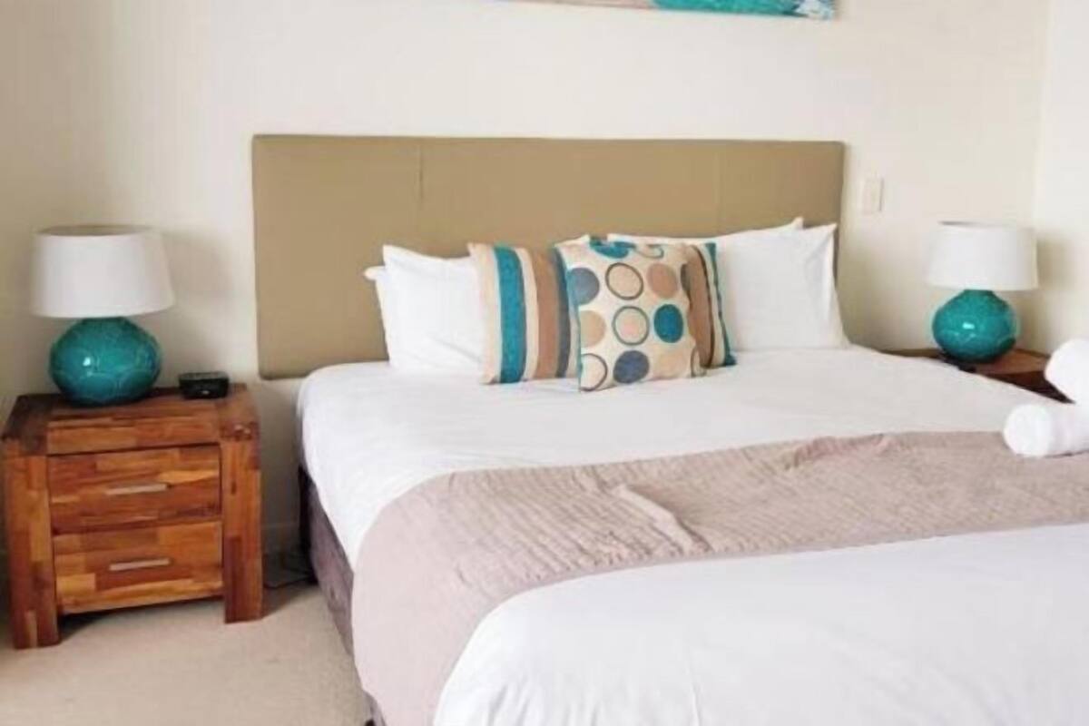 A bedroom with a bed, two bedside tables, and two lamps.