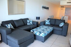 A modern living room with a sectional sofa, a coffee table, and a side table. - Blue C Coolangatta (Coolangatta)