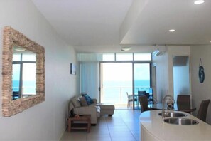 A modern living room with a sofa, a dining table, and a kitchen area with a sink.