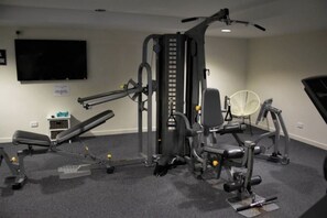 A home gym with a multi-functional exercise machine, a bench, and a fan. - Blue C Coolangatta (Coolangatta)