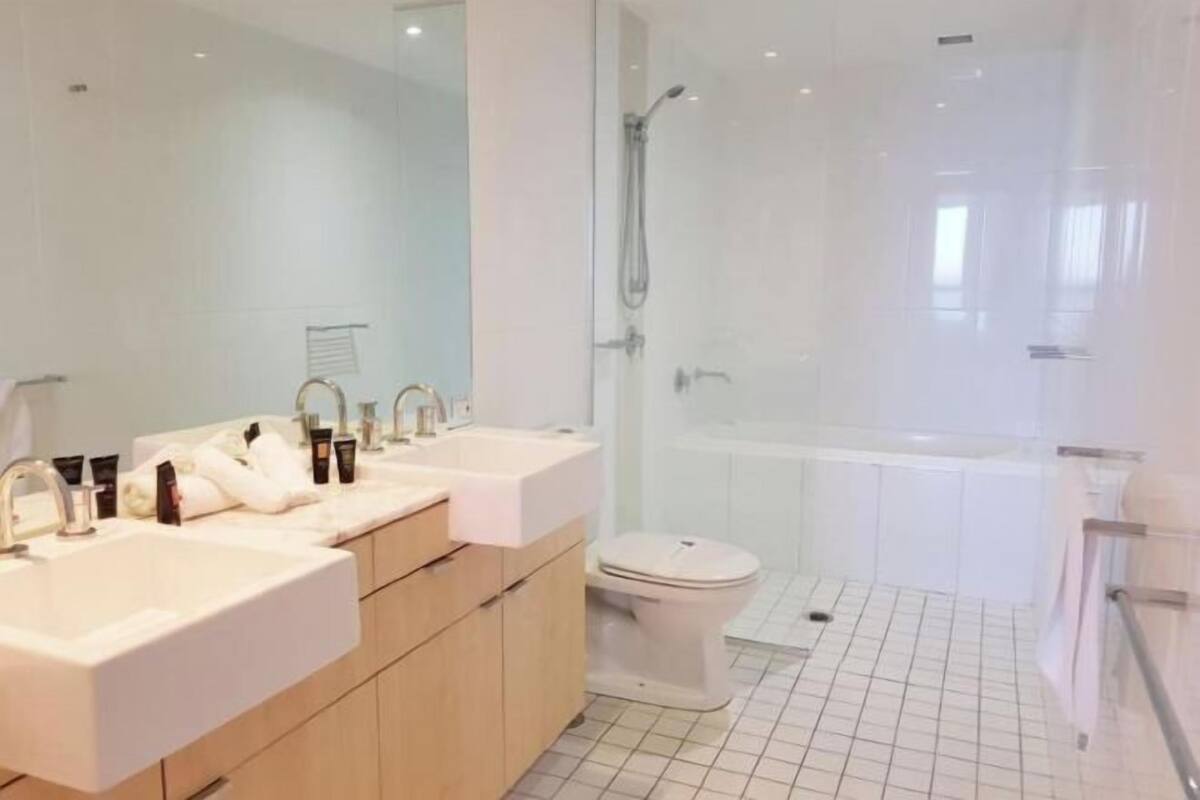 A modern bathroom with two sinks, a toilet, and a glass-enclosed shower area.