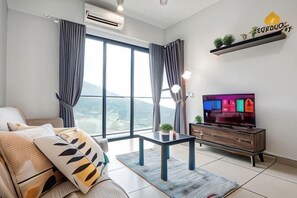 A modern living room with a sofa, a TV, a coffee table, and a view of the outdoors. - Urban Cottage@Midhill Genting Highlands (Free Wi-Fi) (Genting Highlands)