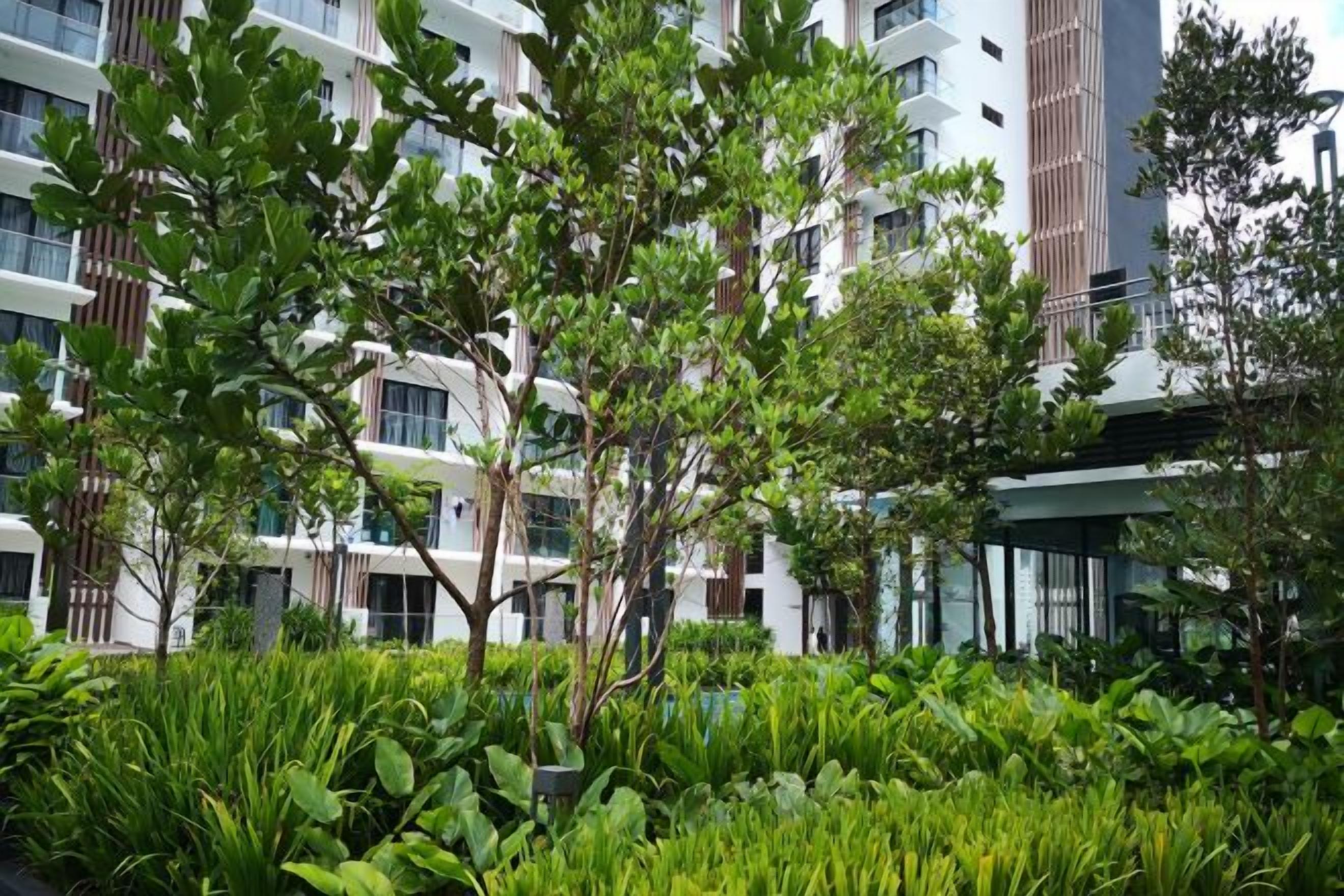 A modern building with multiple floors, surrounded by lush greenery and trees.