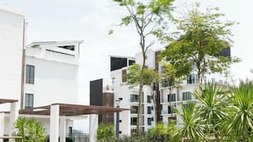A modern residential complex with multiple-story buildings, outdoor seating areas, and greenery.