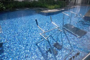 A swimming pool with clear blue water, metal pool chairs, and a tiled deck. - Urban Cottage@Midhill Genting Highlands (Free Wi-Fi) (Genting Highlands)