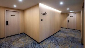 A hotel corridor with wooden doors, a carpet with a leaf pattern, and a sign indicating the hotel name. - Yimi Hotel (Provincial Library Branch near Hainan Institute of Business and Technology) (Haikou)