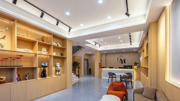 A modern interior with a reception desk, seating area, and open shelving with decorative items. - Yimi Hotel (Provincial Library Branch near Hainan Institute of Business and Technology) (Haikou)