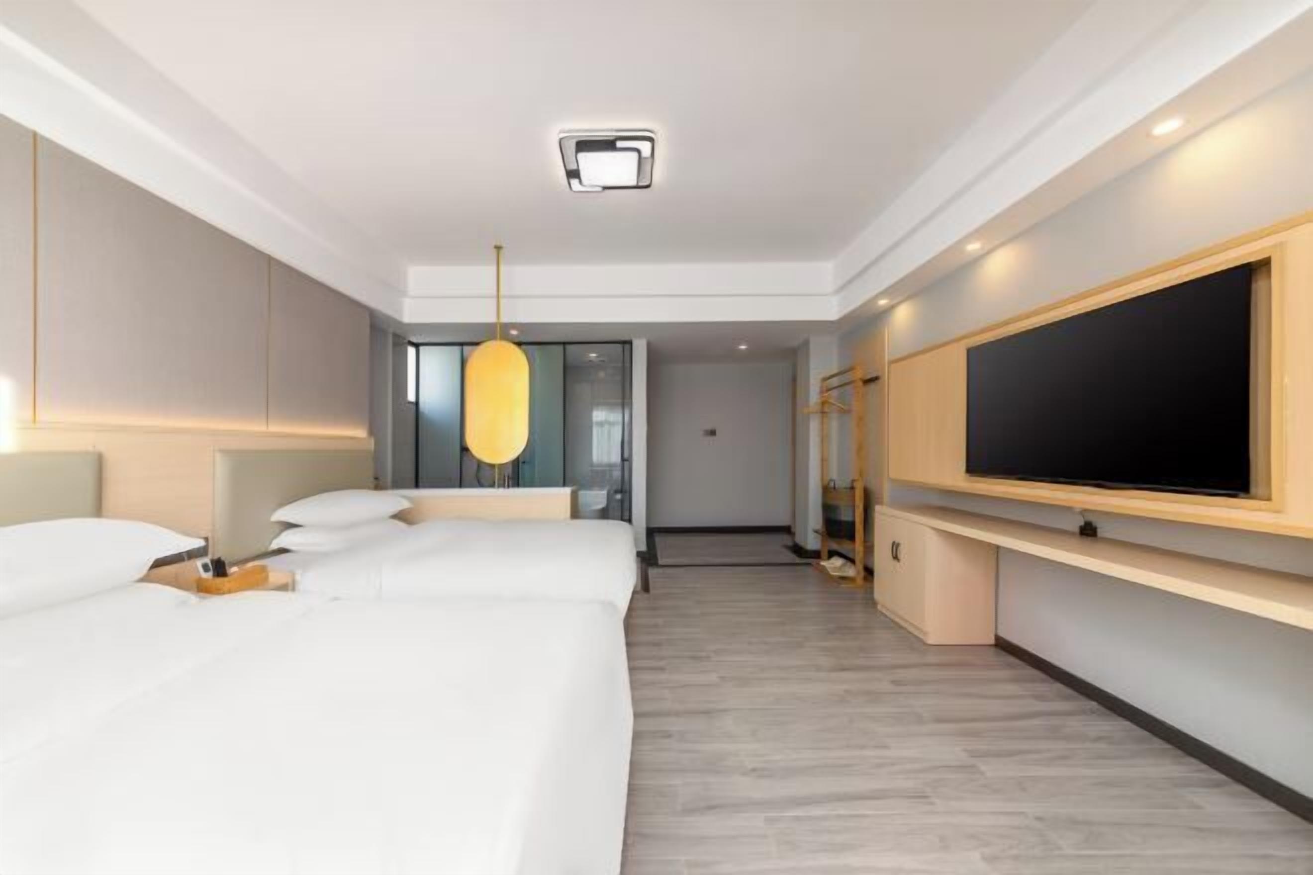 Et moderne hotelværelse med en stor seng, et fladskærms-TV, en loftlampe og et træ-TV-møbel.