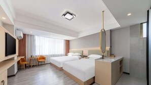 A hotel room with a large bed, a desk with a chair, a TV, and a bathroom with a sink and mirror. - Yimi Hotel (Provincial Library Branch near Hainan Institute of Business and Technology) (Haikou)