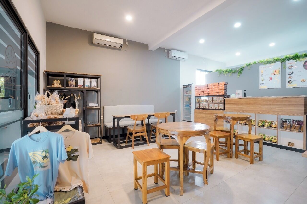 A cafe with wooden furniture, a counter with snacks, and a menu on the wall.