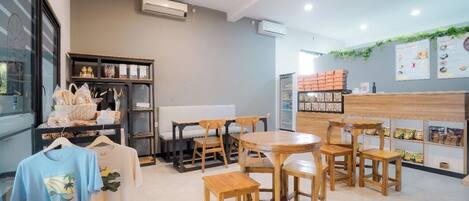 A cafe with wooden furniture, a counter with snacks, and a menu on the wall.