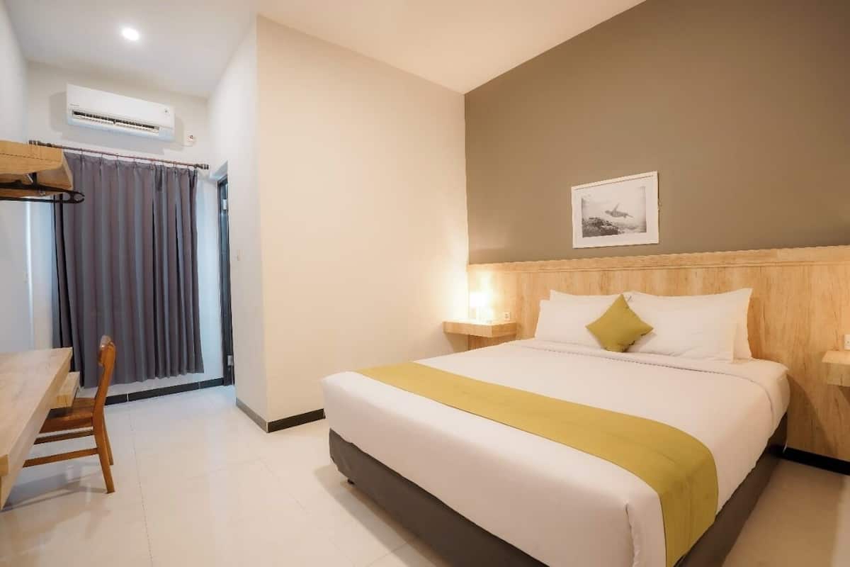 A hotel room with a bed, bedside tables, a desk, and a chair.