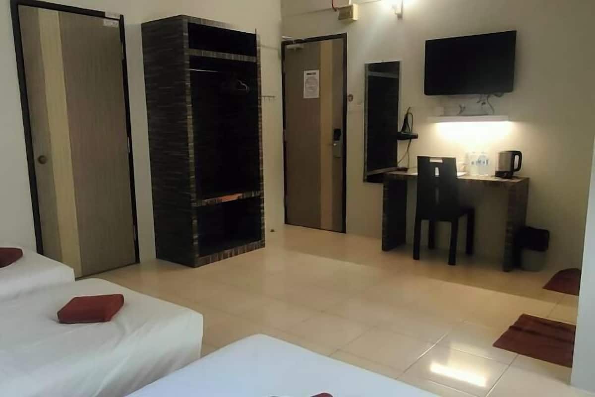Habitació d'hotel amb dos llits, escriptori amb cadira, televisió i mirall.