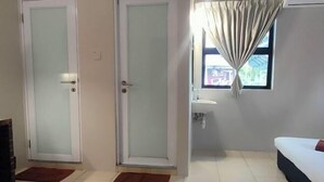 Une pièce avec deux portes, un lit, une fenêtre avec des rideaux et un lavabo.