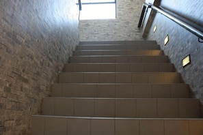 A staircase with a handrail, leading upwards, surrounded by brick walls. - Walk Inn (Miri)