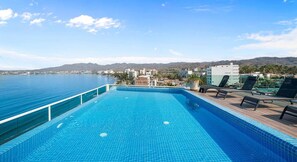 A swimming pool with a view of the sea and buildings in the background.