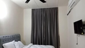 A hotel room with a bed, a ceiling fan, a TV, and a window with curtains. - BUTTERWORTH RAJA UDA RAYA HOMESTAY (Butterworth)