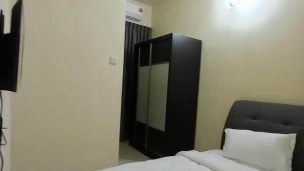 A bedroom with a bed, a wardrobe, and a television. - BUTTERWORTH RAJA UDA RAYA HOMESTAY (Butterworth)