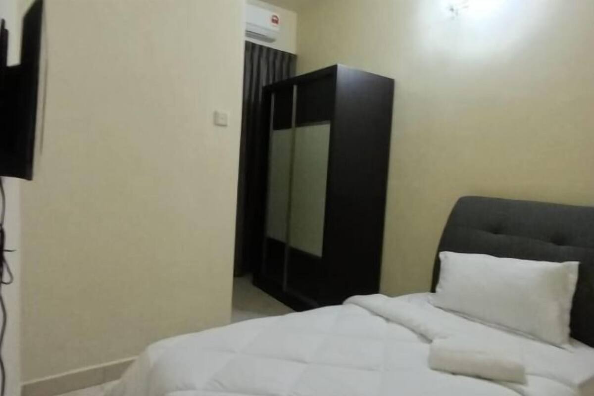 A bedroom with a bed, a wardrobe, and a television.