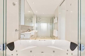 A modern bathroom with a large bathtub, a glass shower enclosure, and a vanity with a mirror.