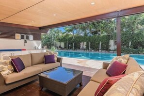 A modern living area with a sofa, coffee table, and a view of a swimming pool.