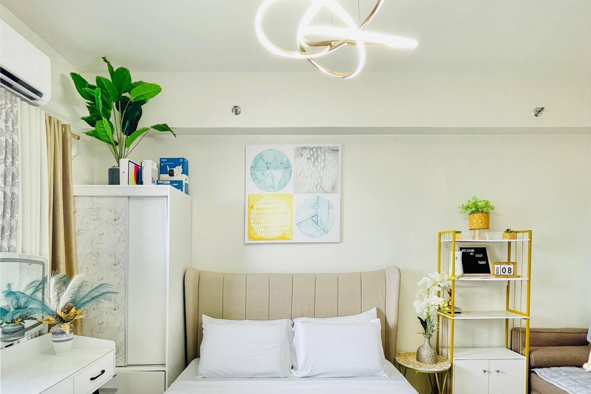Una habitación de hotel moderna con una cama, mesitas de noche, un escritorio y un aire acondicionado instalado en la pared.