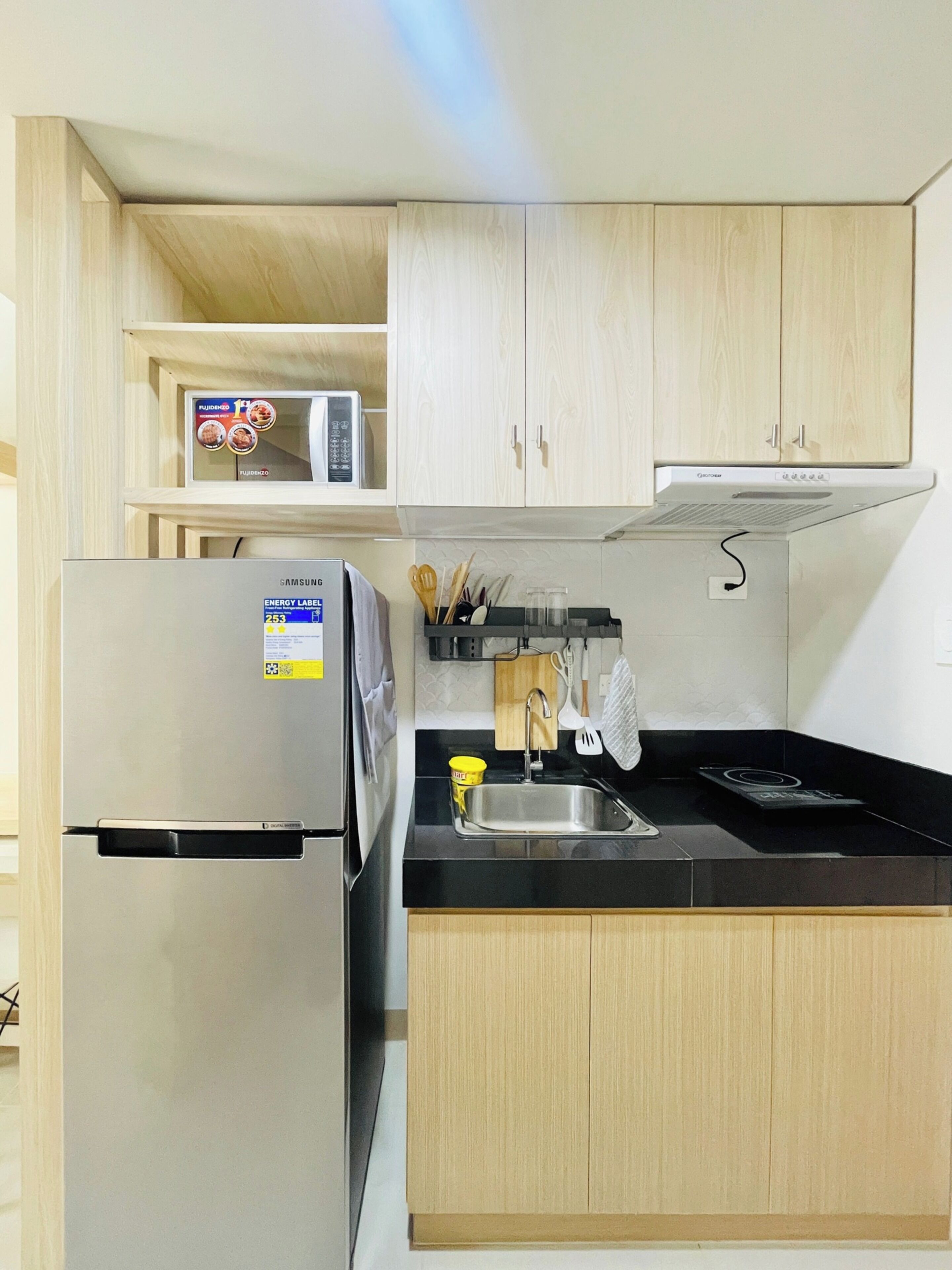 A modern kitchen with a stainless steel refrigerator, a microwave, and a gas stove.