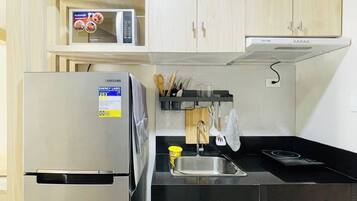 A modern kitchen with a stainless steel refrigerator, a microwave, and a gas stove.