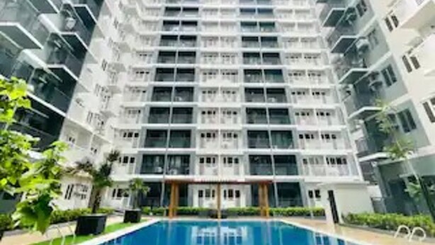 Un immeuble résidentiel de grande hauteur doté d’une cour intérieure où se trouve une piscine.