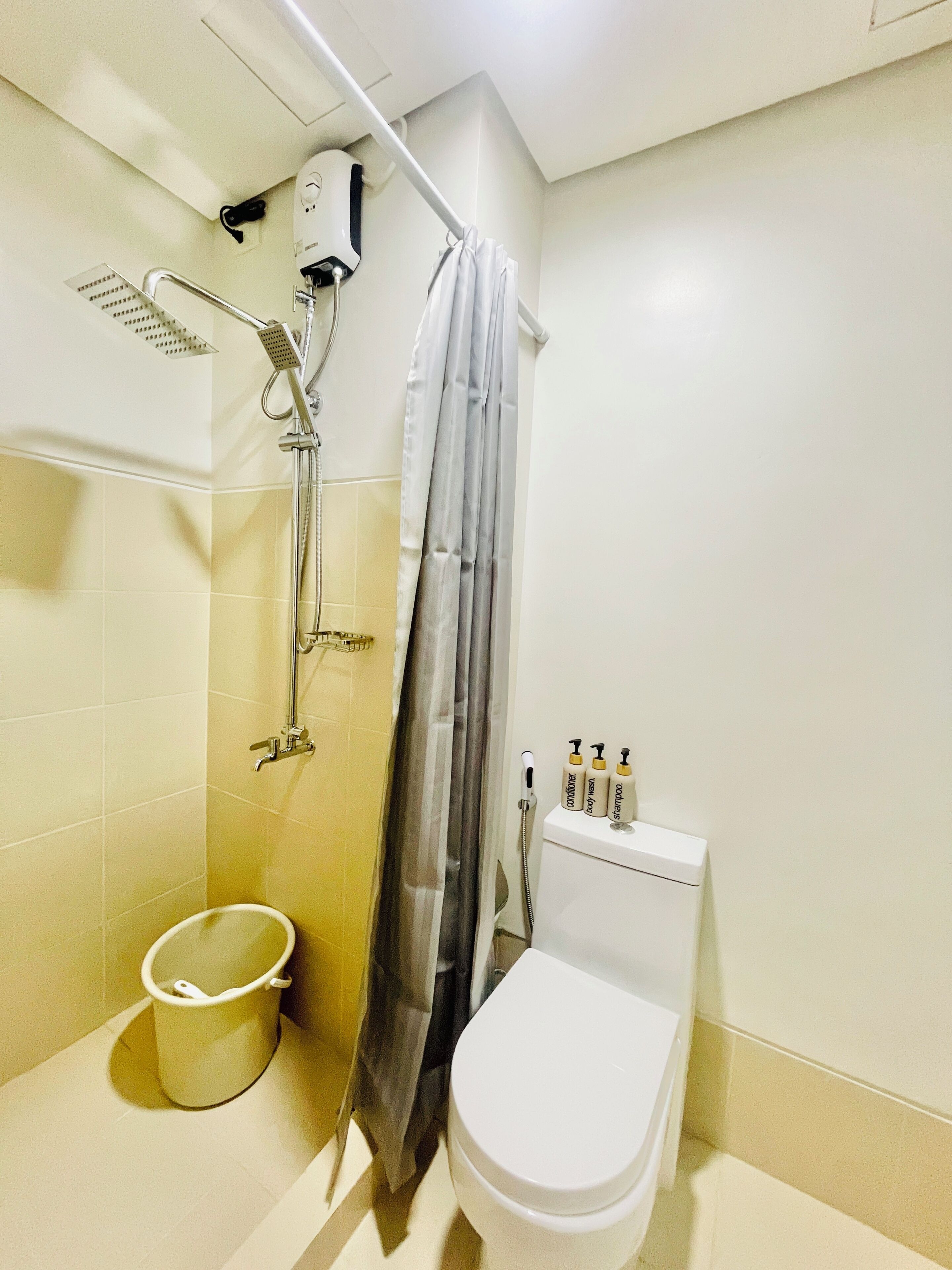 Et badeværelse med brusebad, toilet og en balje.