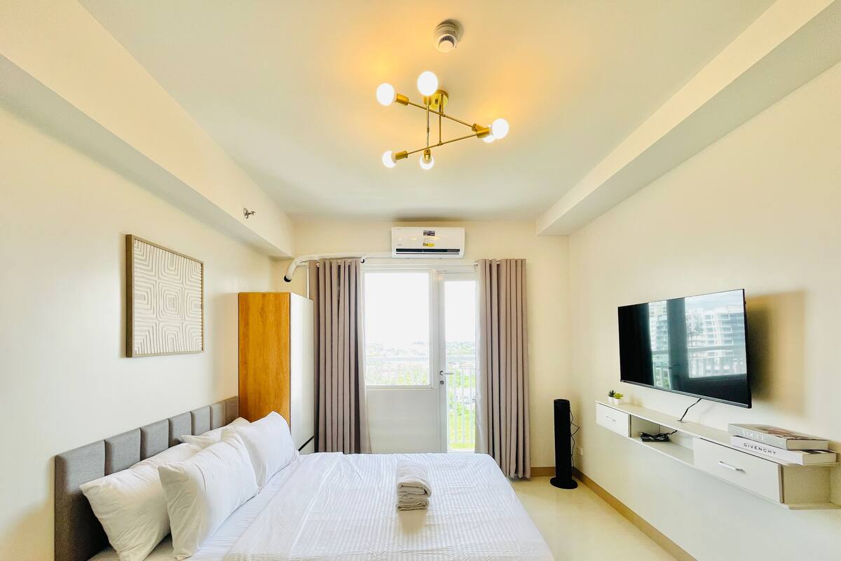 Una habitación de hotel con cama, televisor, aire acondicionado y una ventana con cortinas.