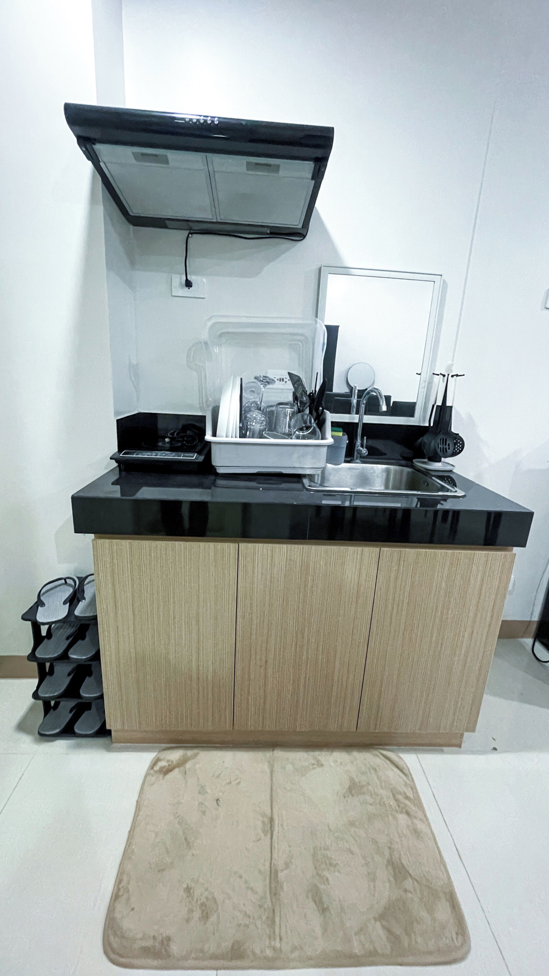 A compact kitchen with a black countertop, wooden cabinets, a built-in oven, and a sink.