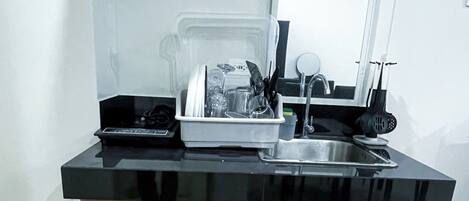 A compact kitchen with a black countertop, wooden cabinets, a built-in oven, and a sink.