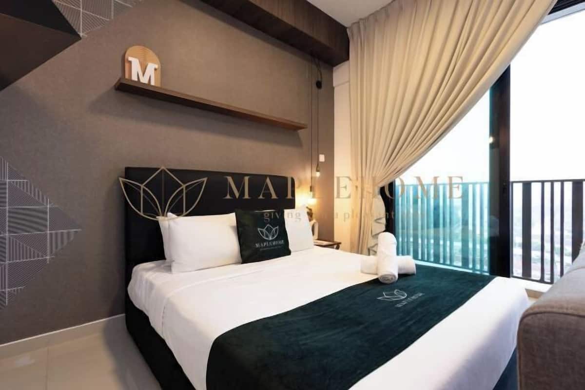 Una habitación de hotel con cama, cabecera con la palabra 'MAIDEN', pared con patrones geométricos y balcón con cortinas.