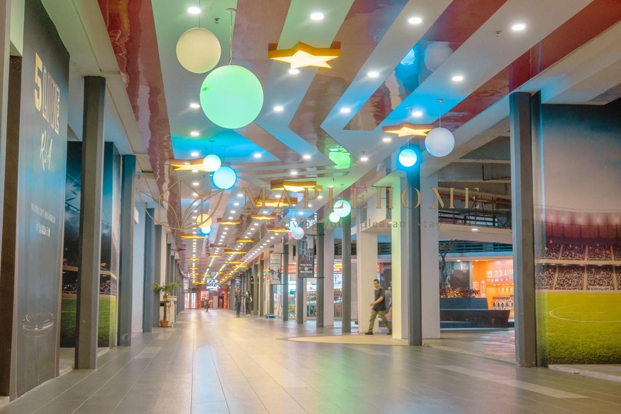 A corridor with a high ceiling, recessed lighting, and a sports field mural on the right wall.